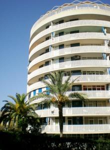 a tall white building with palm trees in front of it at Acapulco Sol Central Lloret in Lloret de Mar