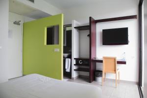 a room with a bed and a desk with a television at ONOMO Hotel Libreville in Libreville
