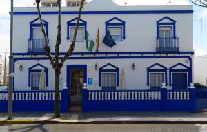 un edificio azul y blanco con un árbol delante en Hostal El Puerto Boutique en Chipiona