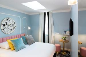 パリにあるオテル パステル パリの白いベッドと青い壁が備わるベッドルーム1室が備わります。