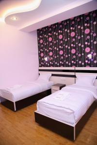 two beds in a room with a black and white wallpaper at Hotel For You in Yerevan