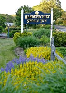 a sign in a garden with purple and yellow flowers at Handkerchief Shoals Inn in Harwich