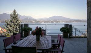 een houten tafel en stoelen met uitzicht op het water bij Paola's Apartment in Belgirate +34 foto's
