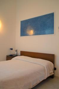 Riva Beach Apartment في ريفا ليجوري: غرفة نوم بسرير ودهان على الحائط