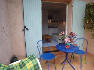 een blauwe tafel met stoelen en bloemen op een patio bij Le Mas des Gardettes in Saint-Paul-de-Vence