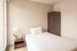 1 dormitorio con cama blanca y armario de madera en City Résidence Chelles, en Chelles