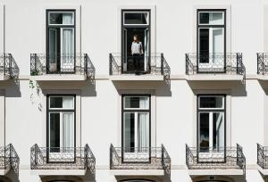 a man stands on a balcony of a building at The Lisboans Apartments in Lisbon
