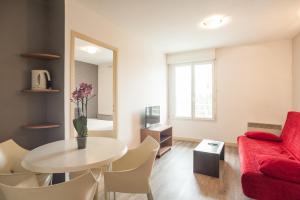 a living room with a red couch and a table at City Résidence Chelles in Chelles