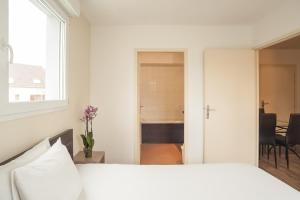 a white bedroom with a bed and a window at City Résidence Chelles in Chelles