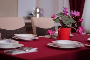 a red table with plates and a vase with flowers at Rumi Apartments in Sarajevo