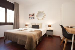 a white bedroom with a bed and a desk and a desk at Click&Flat Europa Fira Apartments in Hospitalet de Llobregat