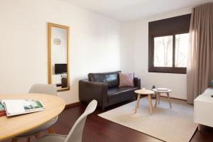 a living room with a black leather couch and a table at Click&Flat Europa Fira Apartments in Hospitalet de Llobregat