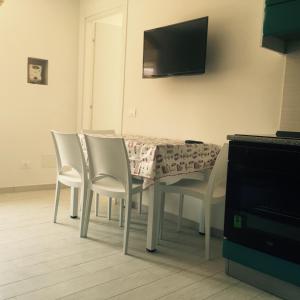 tavolo da pranzo con sedie bianche e televisore di Trilocale Porto Azzurro a Porto Azzurro