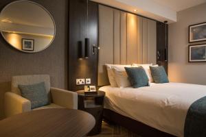 um quarto de hotel com uma cama, uma cadeira e um espelho em Crowne Plaza Basingstoke, an IHG Hotel em Basingstoke