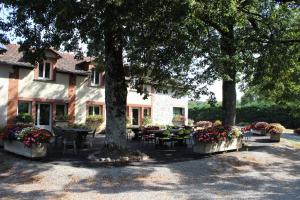 a table and chairs under a tree in front of a house at Auberge de la Normandie in Junhac