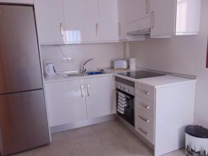a kitchen with white cabinets and a sink and a refrigerator at Duplex 8 in Puerto de Mazarrón