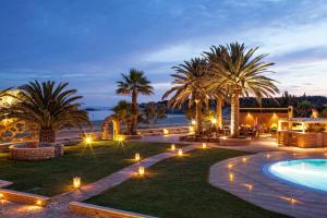 a resort with a pool and palm trees and lights at Finikas Hotel in Aliko Beach