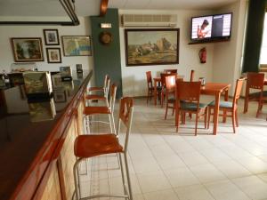 a restaurant with a bar and tables and chairs at Hotel El Castell in Calafell