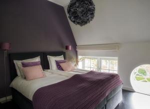 a bedroom with a large bed with purple sheets and pillows at B&B Buitenplaats Natuurlijk Goed in Oosterwolde