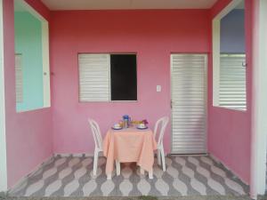 a table and chairs in a room with a pink wall at Pousada Praia de Tairu in Armação do Tairu