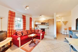 ein Wohnzimmer mit einem roten Sofa und einer Küche in der Unterkunft Landhaus Will in Hilders