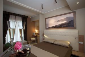 a bedroom with a bed and a table with a pink rose at Hotel C'era Una Volta in Castiglione della Pescaia