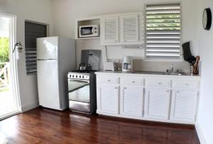 a kitchen with white cabinets and a white refrigerator at Oasis Marigot in Marigot Bay