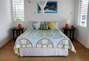 a bedroom with a bed with two night stands and two windows at Oasis Marigot in Marigot Bay
