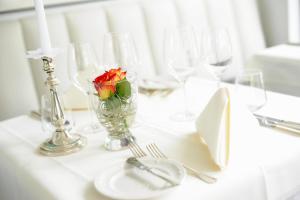a white table with a vase with a flower in it at Hotel Restaurant Sengscheider Hof in Sankt Ingbert