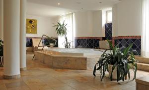 - une grande salle de bains pourvue d'une baignoire avec des plantes dans l'établissement Hotel Restaurant Sengscheider Hof, à Saint-Ingbert