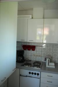 a kitchen with a stove and white cabinets at Ferienappartement mit Schwimmbad und Alpenblick in Höchenschwand