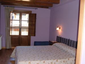 a bedroom with a bed and a window and a door at Hostal Rural Aude in Durro