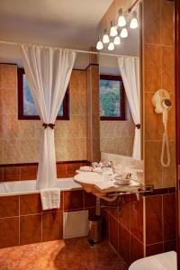 y baño con lavabo, bañera y espejo. en Hotel Nemira, en Slănic-Moldova