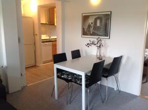 a white dining room table with chairs and a vase with flowers at Klitgaards Holiday Apartment in Mejeriby