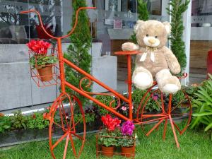 a teddy bear sitting on a orange bicycle with flowers at Vivas Hotel e Casa in Monte Sião