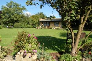 a house with a green yard with flowers at Stow Lodge Hotel in Stow on the Wold