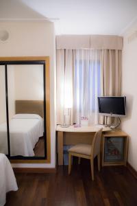 a bedroom with a desk with a mirror and a bed at Hotel Inglaterra in Granada