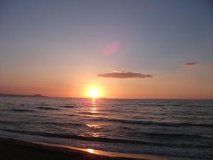 a sunset on the beach with the ocean at Almyra Apartments & Suites in Sfakaki