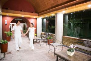 a man and a woman walking down a patio at Hotel Los Olivos Spa in Oaxaca City