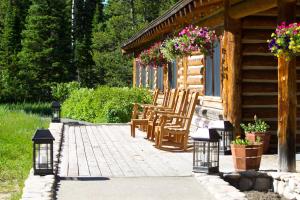 a porch of a log cabin with chairs and flowers at Jenny Lake Lodge in Beaver Creek