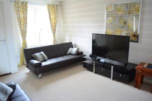 a living room with a black couch and a flat screen tv at Glasgow Hampden House in Glasgow