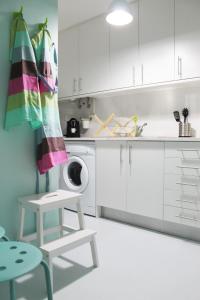 a white kitchen with a washing machine and a stool at Window to Lisboa II in Lisbon