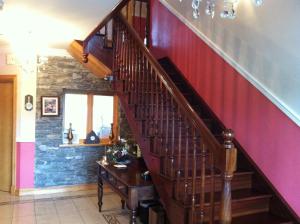 a wooden staircase in a room with a red curtain at DunnCourt House in Killarney