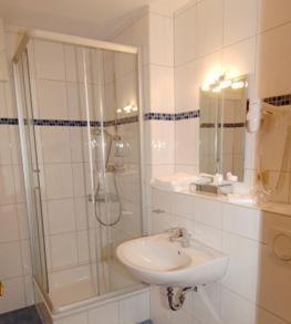 a white bathroom with a shower and a sink at Hotel-Restaurant Bürgerstuben in Lebach