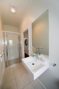 a white bathroom with a sink and a shower at Bank House Tamborine Mountain in Mount Tamborine