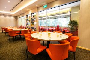 un restaurant avec des tables blanches et des chaises orange dans l'établissement Metro Y Hotel Singapore, à Singapour