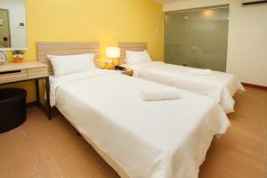 a hotel room with two beds and a desk at Hotel Sentral Kuala Terengganu in Kuala Terengganu