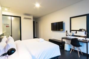 a bedroom with a bed and a desk and a mirror at BED Chiangmai Gate- Adults Only in Chiang Mai