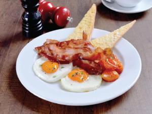 a plate of food with eggs and bacon and crackers at Maitria Hotel Sukhumvit 18 Bangkok – A Chatrium Collection in Bangkok