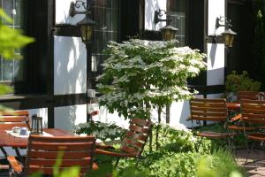 einen Tisch mit Stühlen und einen Baum mit weißen Blumen in der Unterkunft Hotel Vivendi in Herford